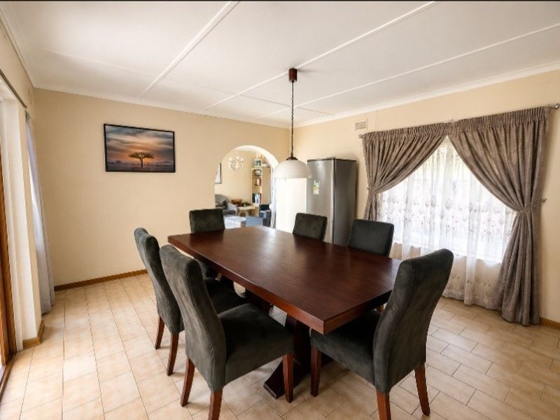 A functional dining room featuring tiled flooring, a classic arched doorway leading to the living area, and a central pendant light fixture.