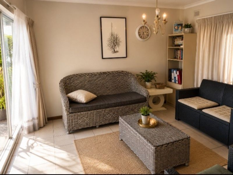 A bright living room featuring tiled flooring and a large sliding glass door providing natural light and access to the outdoor area.