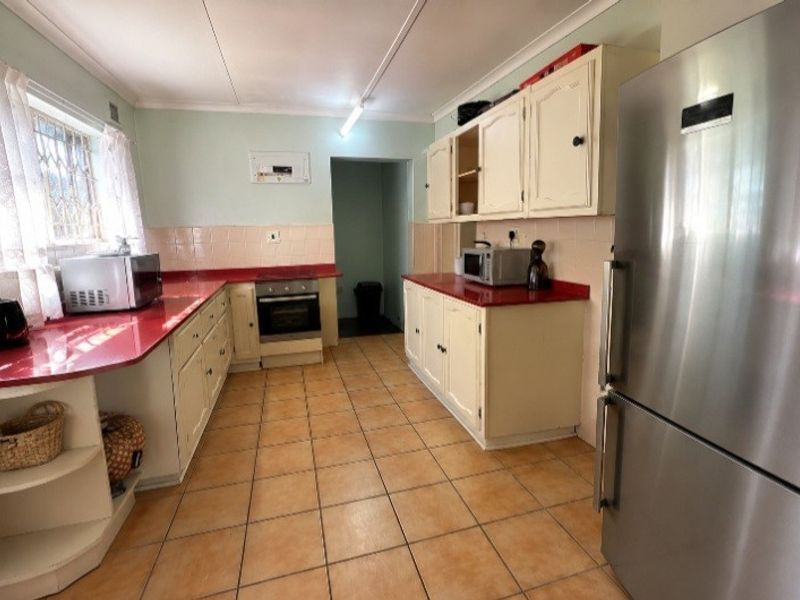 A functional kitchen featuring tiled flooring, built-in cabinetry, and a tiled backsplash, offering a dated aesthetic with potential for modernization.