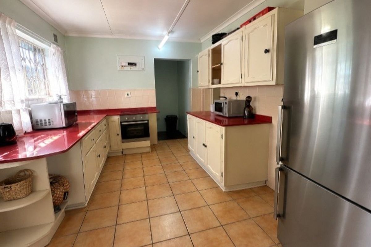 A functional kitchen featuring tiled flooring, built-in cabinetry, and a tiled backsplash, offering a dated aesthetic with potential for modernization.