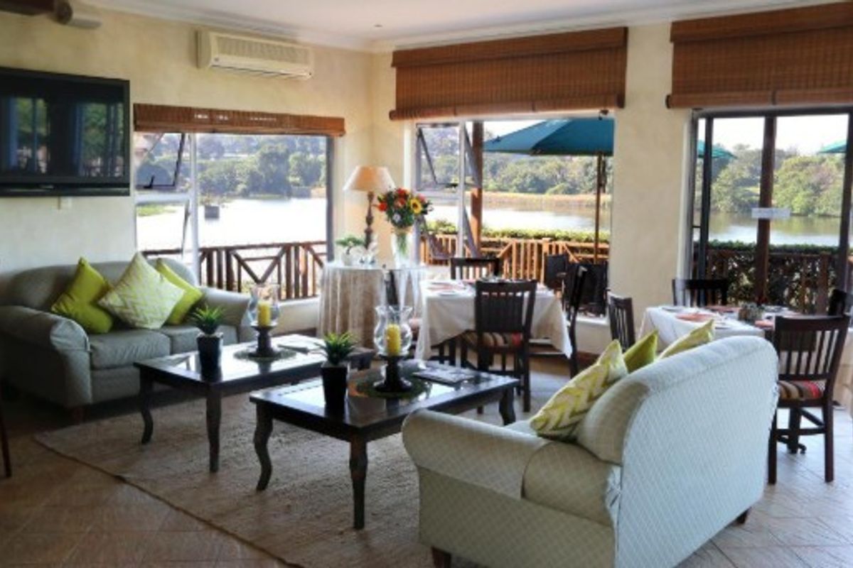 Spacious open-plan office or lounge area featuring tiled floors, split-system air conditioning, and large windows with scenic lake views and access to a deck.