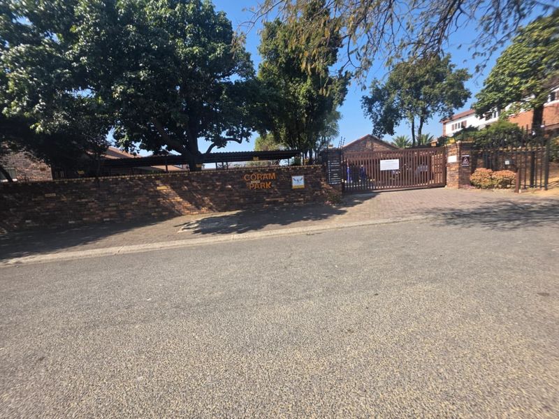 Front entrance view of Coram Park commercial property featuring a brick boundary wall, secure automated gate access, and paved driveway.
