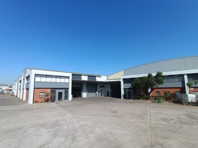 Industrial warehouse complex featuring multiple roller shutter doors, a spacious concrete yard, and a combination of brick and metal cladding exterior finishes.