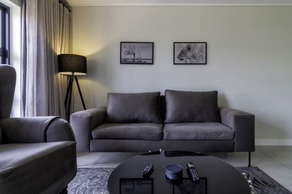 A well-maintained living room featuring neutral tiled flooring and floor-to-ceiling curtain tracks, providing a clean and modern foundation for the space.