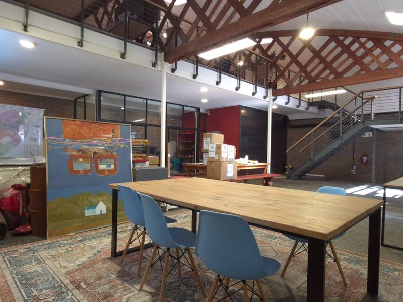 Spacious open-plan retail or office area featuring high ceilings with exposed timber trusses, a mezzanine level, and industrial-style finishes.