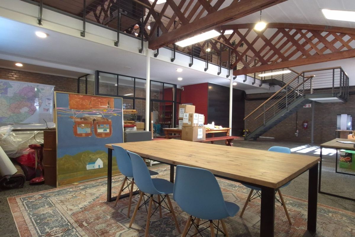 Spacious open-plan retail or office area featuring high ceilings with exposed timber trusses, a mezzanine level, and industrial-style finishes.