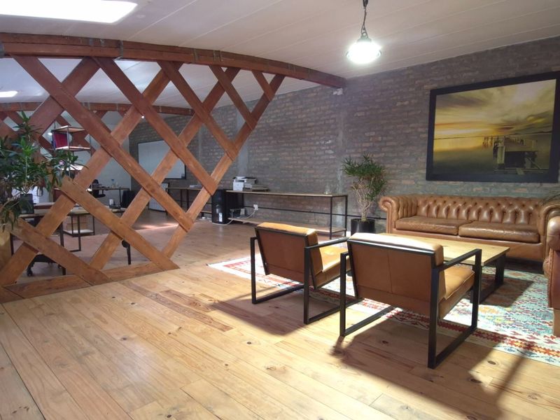 Spacious retail or office lounge area featuring exposed brick walls, warm timber flooring, and a decorative timber lattice partition.