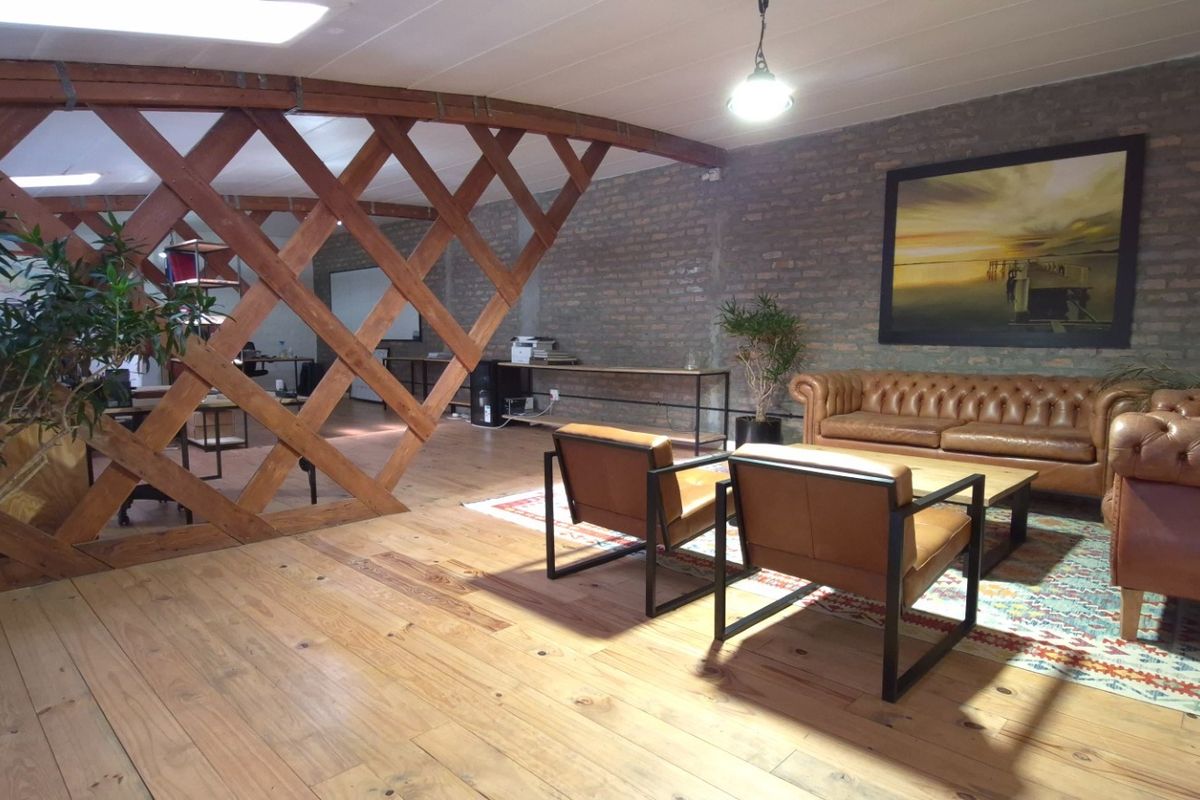 Spacious retail or office lounge area featuring exposed brick walls, warm timber flooring, and a decorative timber lattice partition.