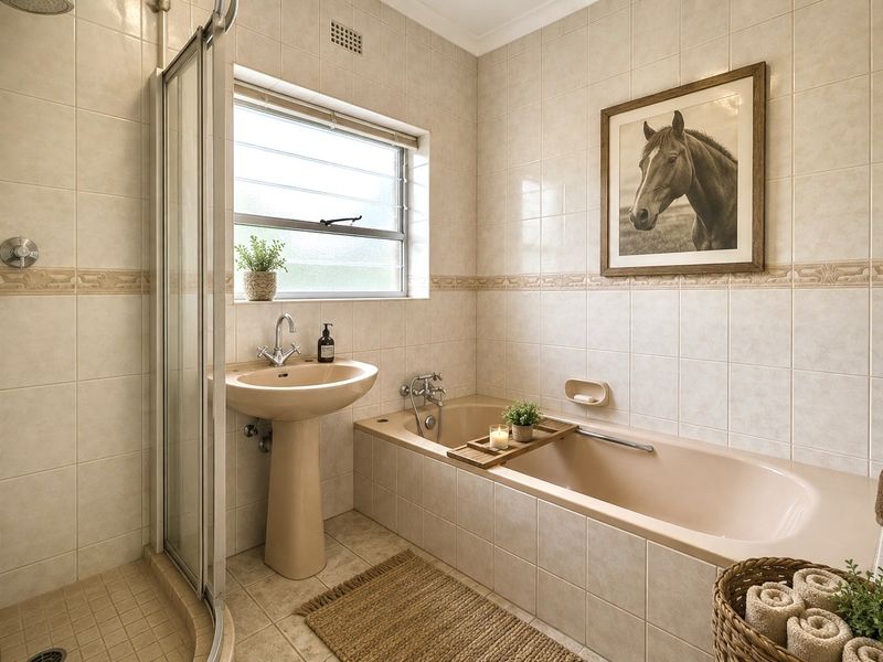 A functional bathroom featuring a pedestal basin, built-in bathtub, and a separate shower enclosure with neutral wall and floor tiling.