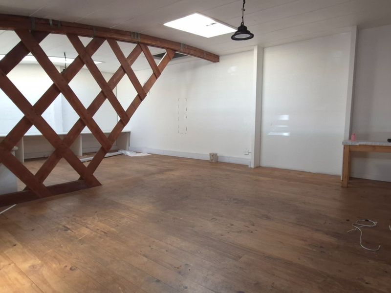 Open-plan office space featuring timber lattice partitions, natural timber flooring, and a skylight, offering a versatile commercial work environment.