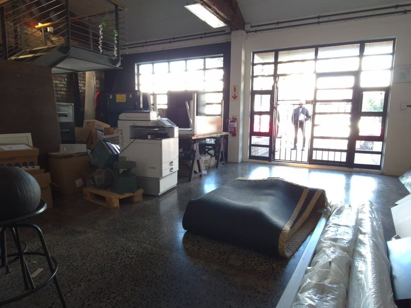 Spacious industrial-style open plan commercial area featuring polished concrete floors, exposed timber beams, and large steel-framed windows providing ample natural light.