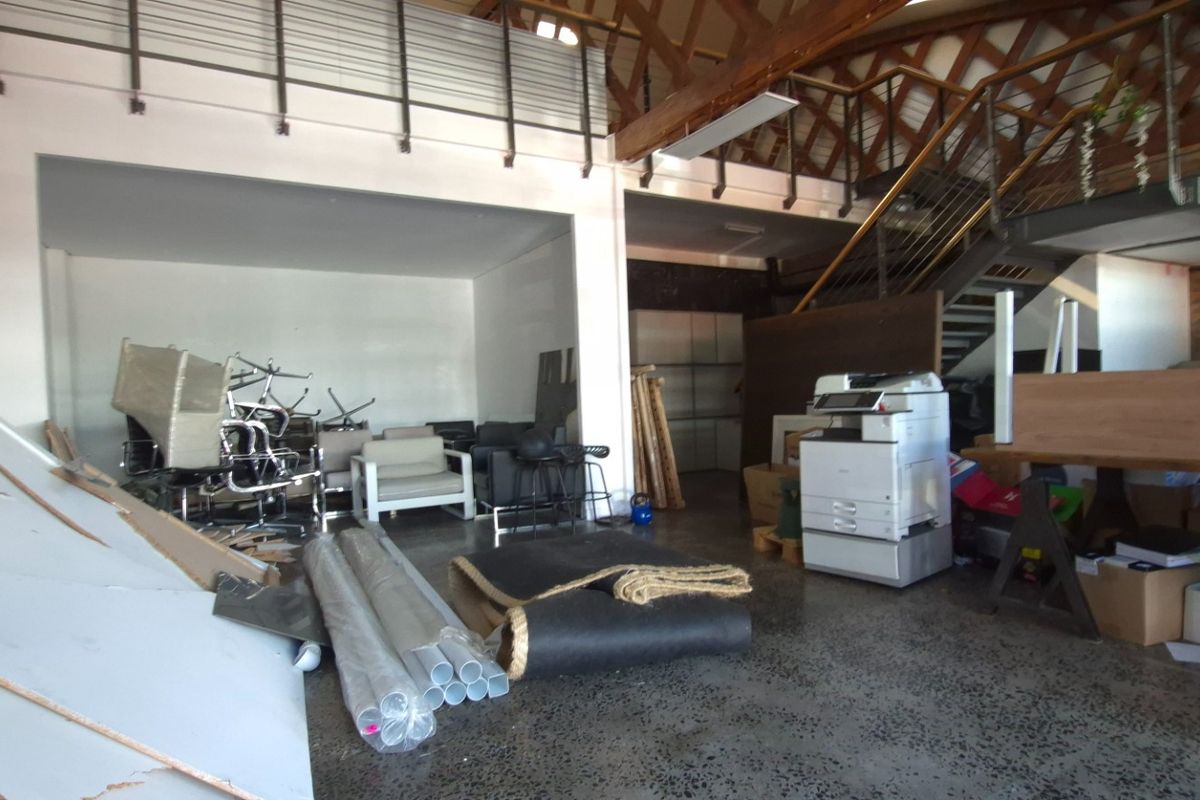 Spacious open-plan commercial area featuring a mezzanine level, exposed timber roof trusses, steel staircase, and polished concrete flooring.