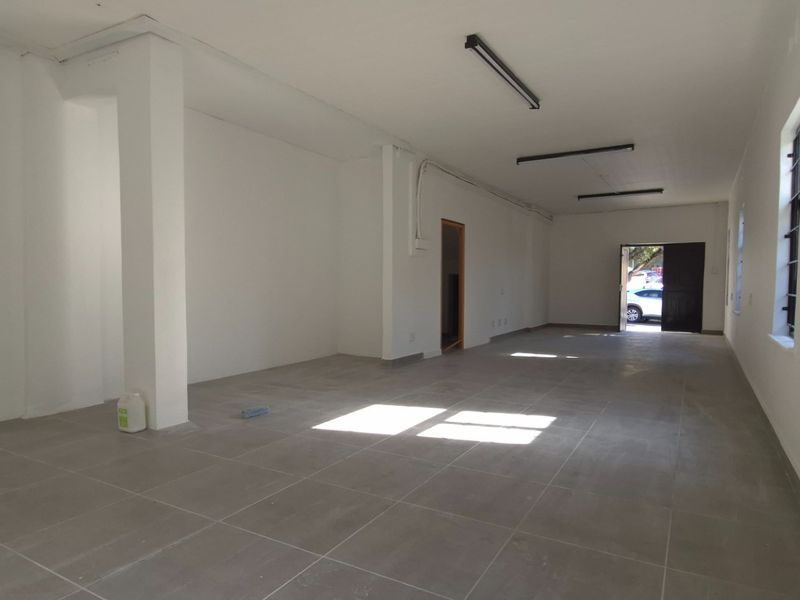 A spacious, vacant open-plan retail area featuring neutral tiled flooring, clean white walls, and functional strip lighting, ready for custom fit-out.