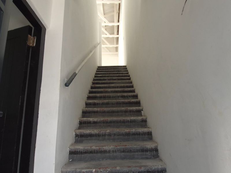 A functional staircase area featuring a handrail and exposed roof trusses, currently in an unfinished state awaiting final flooring and cosmetic finishes.