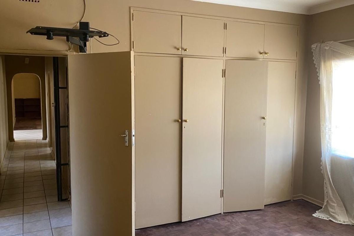 A bedroom featuring built-in cupboards with overhead storage and tiled flooring, offering a functional space ready for modernization.