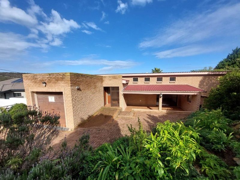 Front elevation of a single-story brick house featuring a paved driveway, integrated garage, and a covered entrance area.