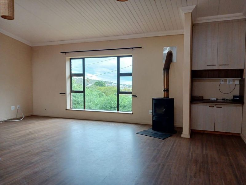 Spacious living area featuring a wood-burning stove, built-in cabinetry, laminate flooring, and a large window with scenic views.
