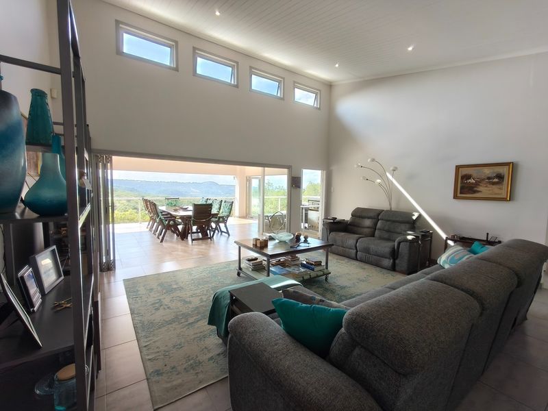 Spacious open-plan living area featuring high vaulted ceilings, clerestory windows, and large stacking doors that open onto a scenic outdoor patio.