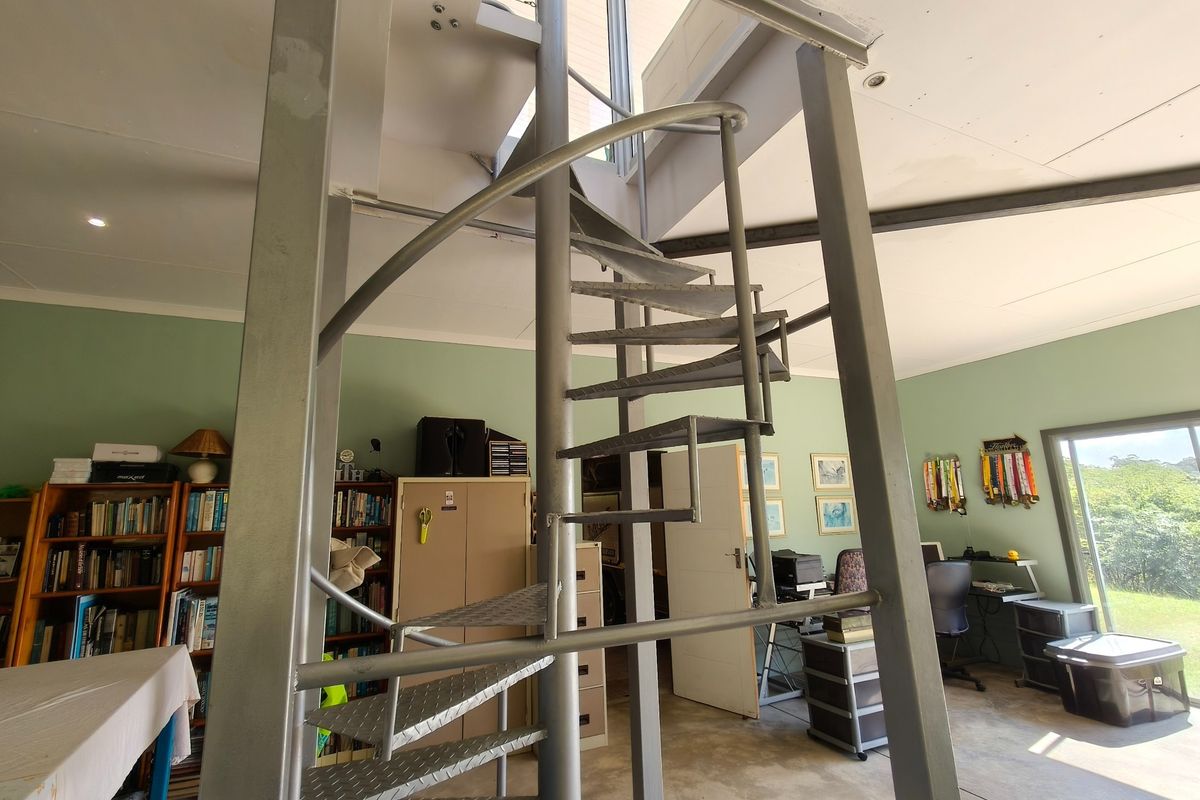 A living area featuring a prominent metal spiral staircase, neutral wall finishes, and sliding glass doors providing access to the exterior.