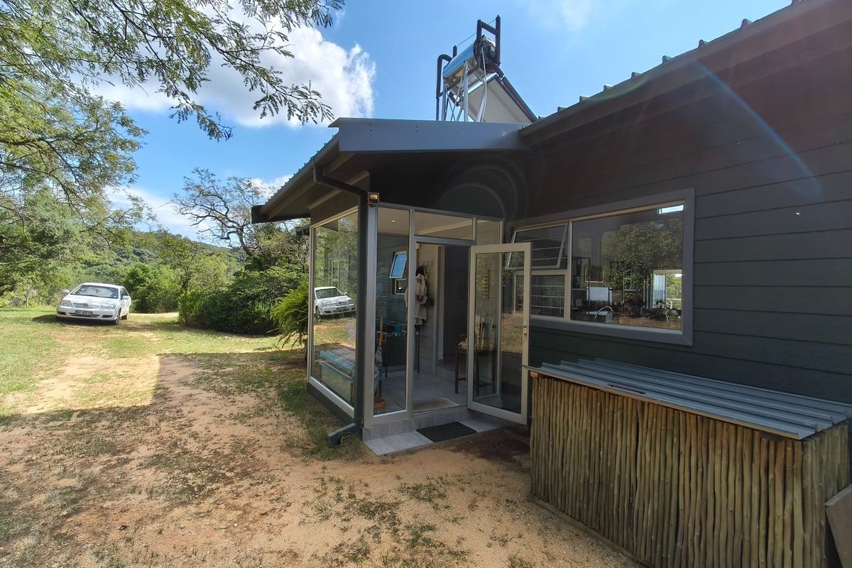 Rear view of the farm dwelling featuring timber cladding, aluminium window frames, and a roof-mounted solar water heating system.