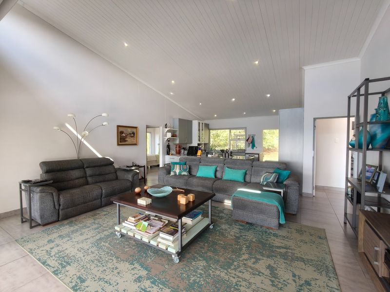 Spacious open-plan living area featuring a vaulted tongue and groove ceiling, recessed lighting, and tiled floors, seamlessly connecting to the kitchen.