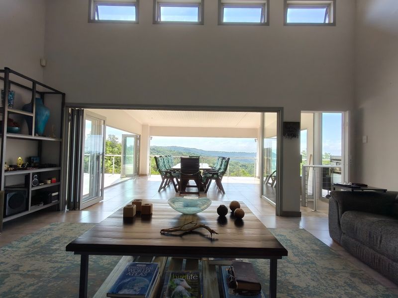Spacious open-plan living area featuring high ceilings with clerestory windows and large bi-fold doors opening onto a covered patio with scenic views.