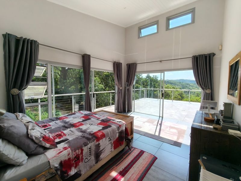 Spacious bedroom featuring high ceilings, large sliding glass doors opening onto a private balcony, and expansive views of the surrounding landscape.