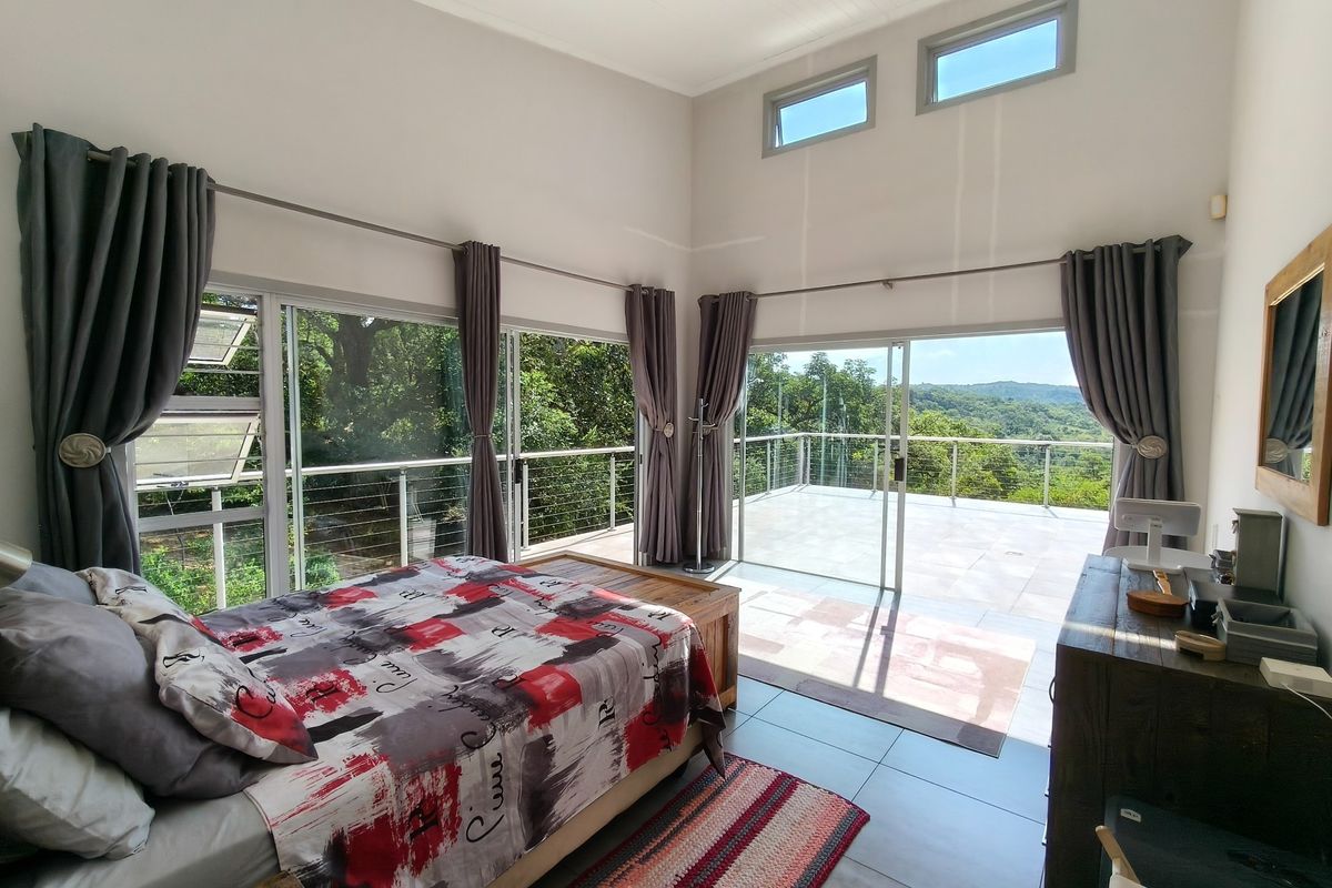 Spacious bedroom featuring high ceilings, large sliding glass doors opening onto a private balcony, and expansive views of the surrounding landscape.
