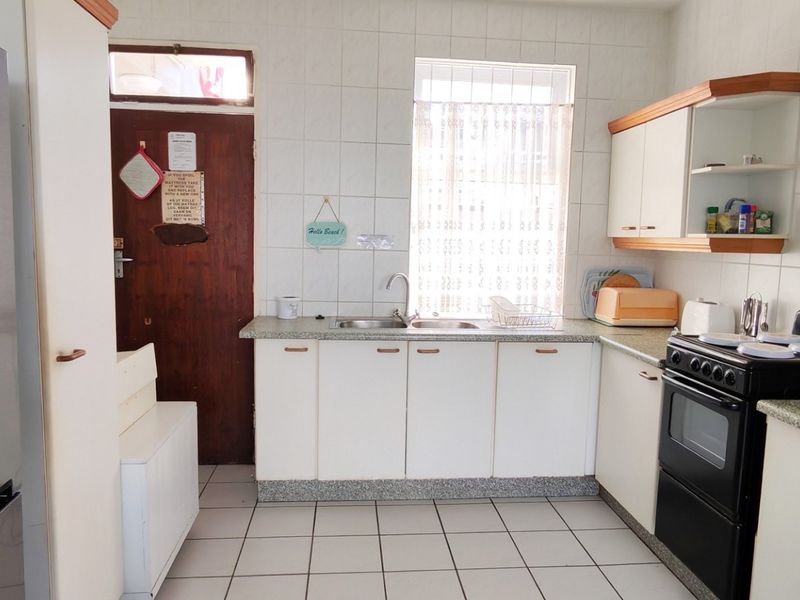A functional kitchen featuring white cabinetry, tiled backsplash, tiled flooring, and a freestanding oven, offering a practical layout for daily meal preparation.