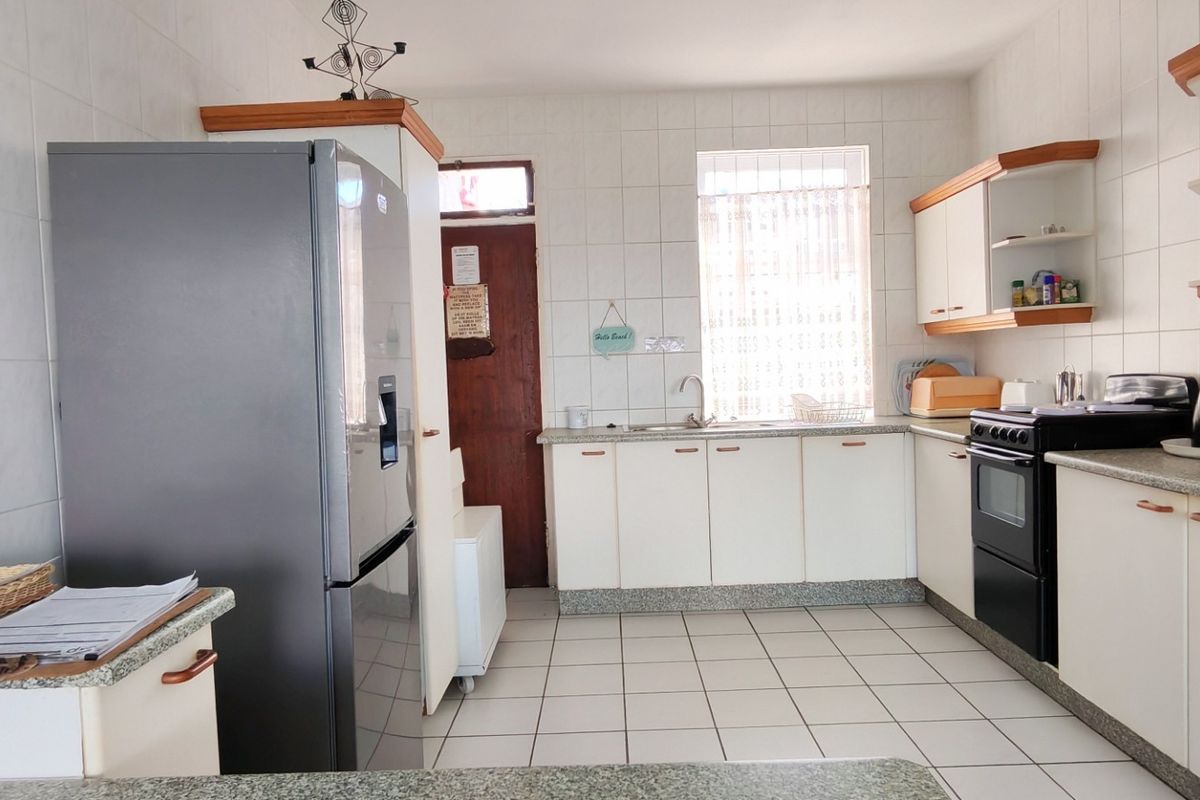 A functional kitchen featuring tiled walls and floors, granite countertops, built-in cabinetry, and a freestanding oven, offering a practical layout for daily use.