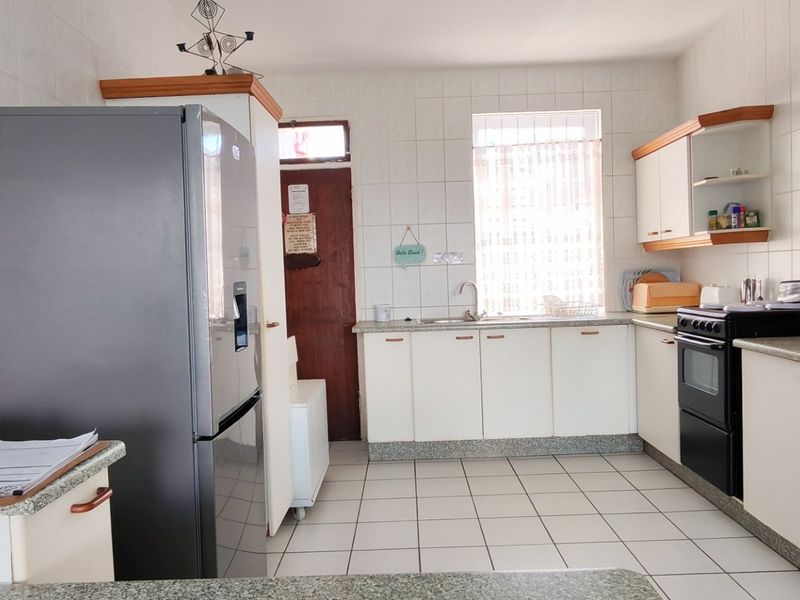 A functional kitchen featuring tiled walls and floors, granite countertops, built-in cabinetry, and a freestanding oven, offering a practical layout for daily use.