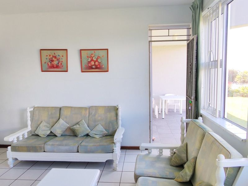 A bright living room featuring tiled flooring and direct access to an outdoor patio area through a security gate.