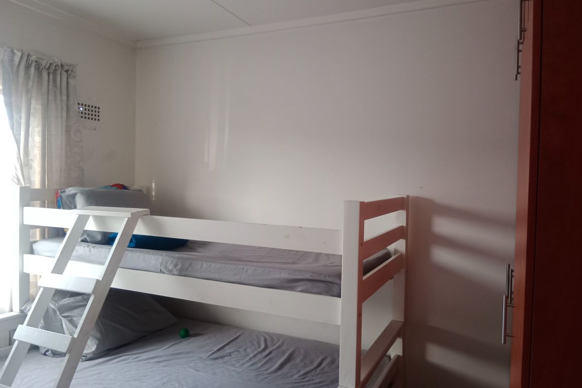 A functional bedroom featuring a built-in cupboard and natural light from the window.
