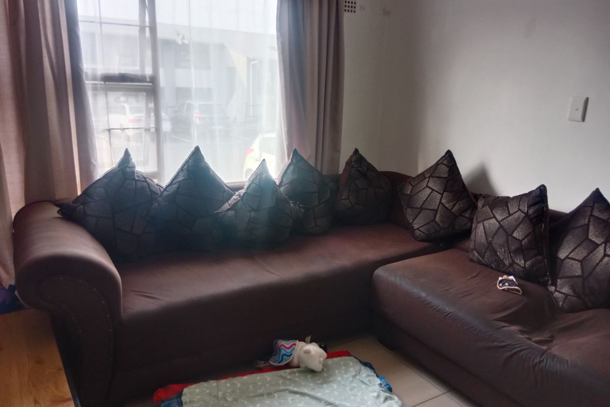 A living room area featuring tiled flooring and a large window, providing natural light to the space.
