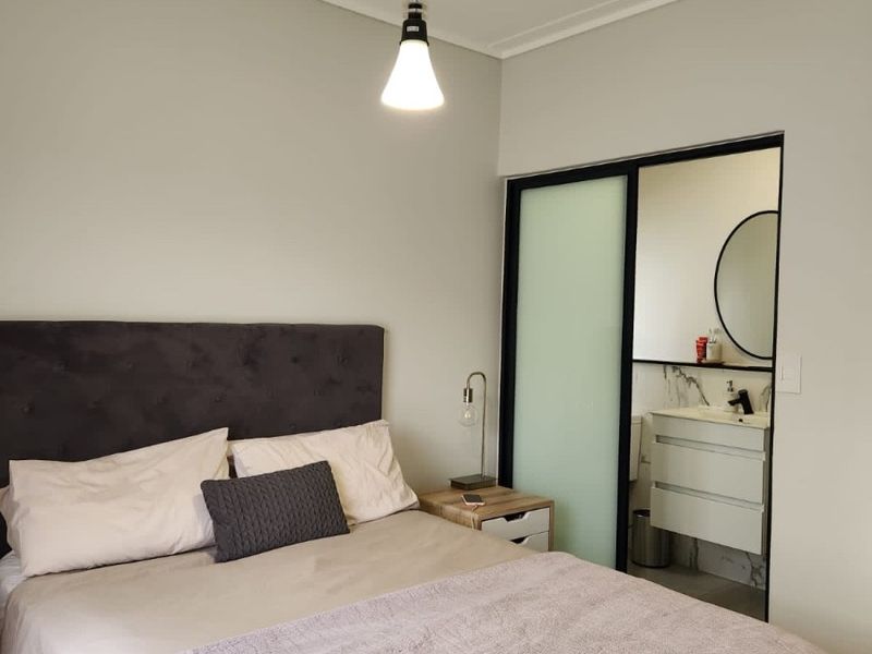 A well-maintained bedroom featuring a modern pendant light and an integrated en-suite bathroom with a vanity and sliding door access.
