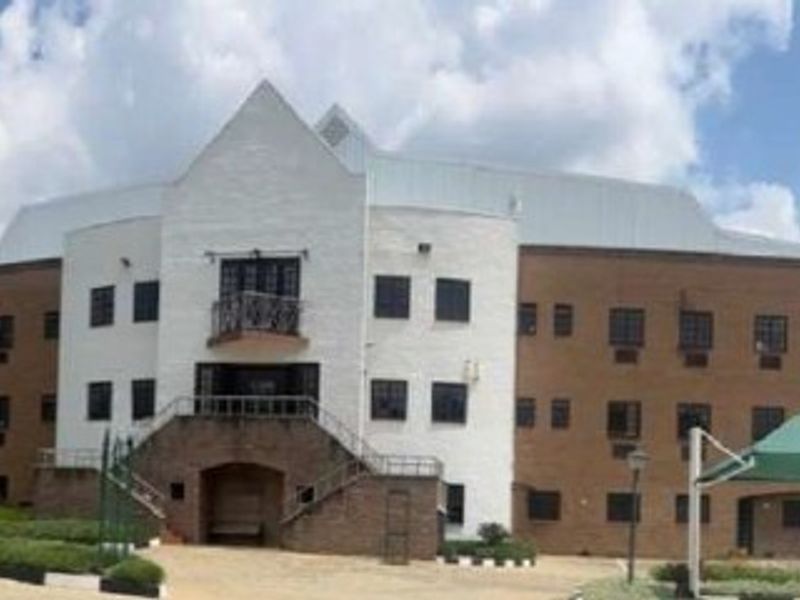 Front elevation of a multi-story industrial or commercial building featuring a brick facade, central staircase, and covered parking area.
