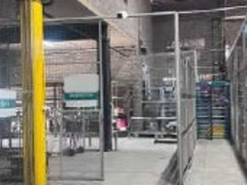 Industrial utility space featuring concrete flooring, exposed brick walls, and secure steel mesh partitioning throughout the facility.