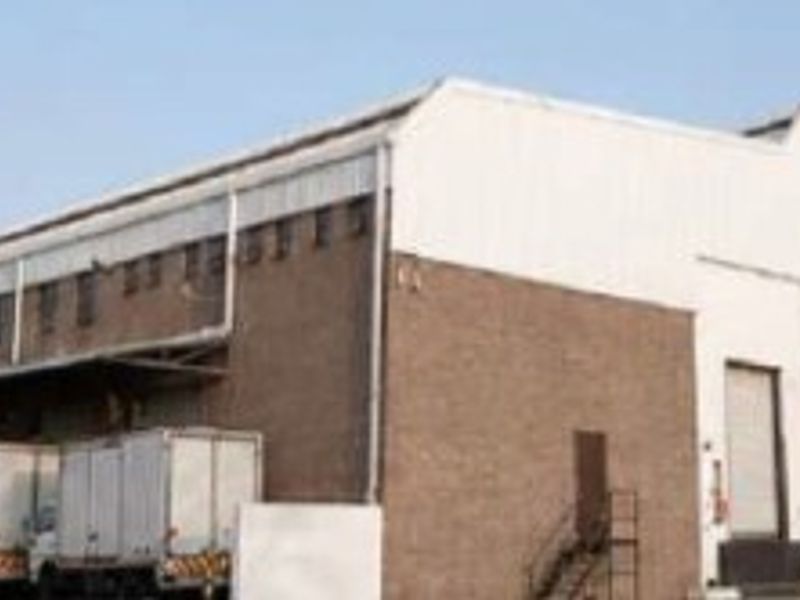 Large industrial warehouse facility featuring multiple loading bays, roller shutter doors, and a functional concrete apron for logistics and distribution operations.