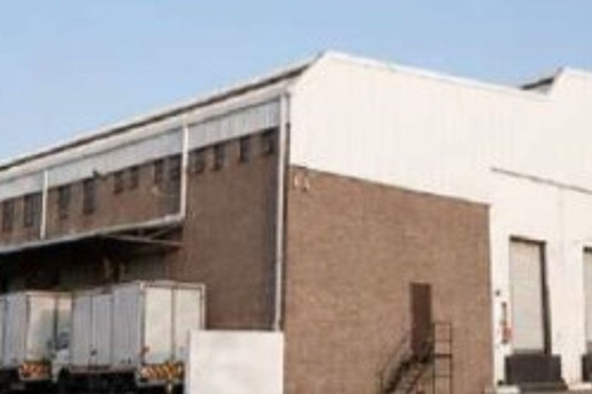 Large industrial warehouse facility featuring multiple loading bays, roller shutter doors, and a functional concrete apron for logistics and distribution operations.