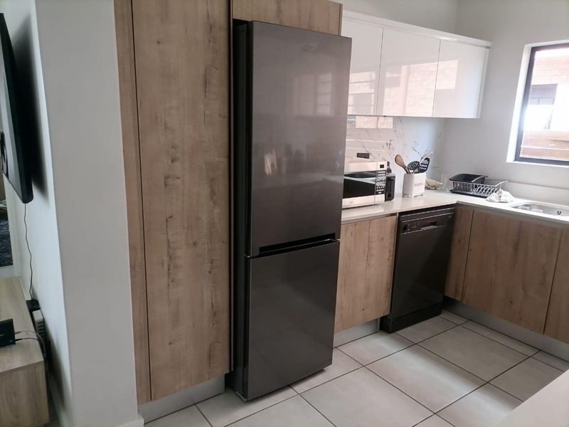 Modern kitchen featuring wood-grain cabinetry, marble-look backsplash, tiled flooring, and integrated appliances in a clean, contemporary layout.