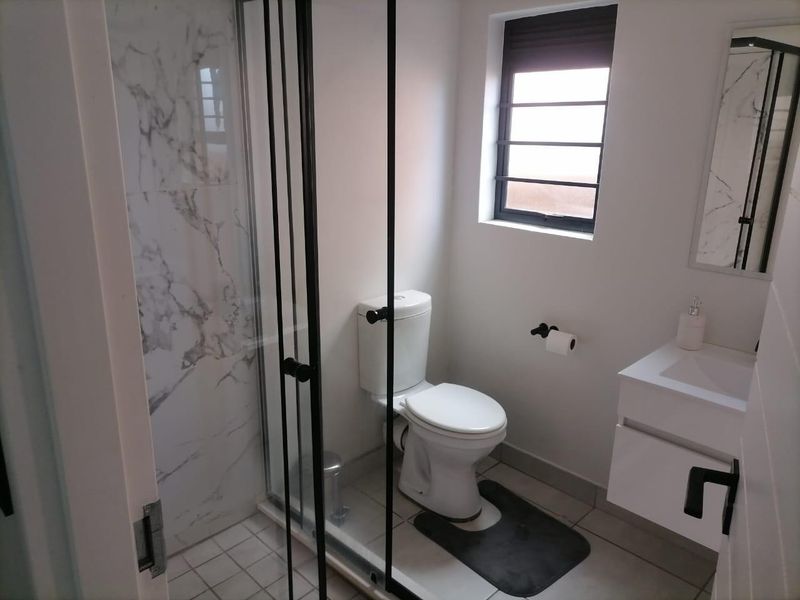 Modern bathroom featuring a glass-enclosed shower with marble-look tiling, a sleek vanity cabinet, and a clean, contemporary design.