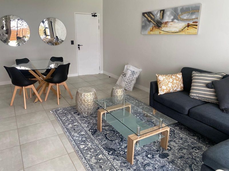 An open-plan living and dining area featuring neutral wall tones and tiled flooring, providing a versatile space for relaxation and meals.