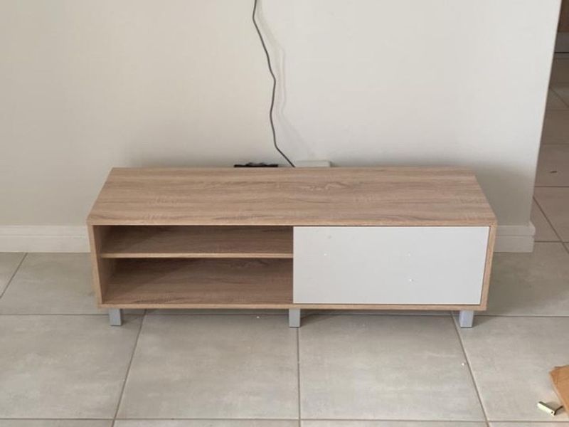 A living room area featuring neutral tiled flooring and a wall-mounted television setup.