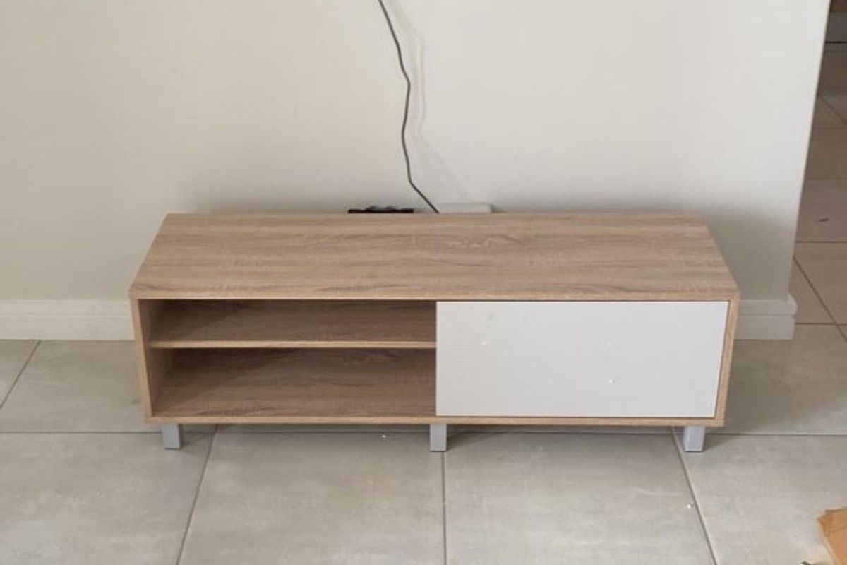 A living room area featuring neutral tiled flooring and a wall-mounted television setup.