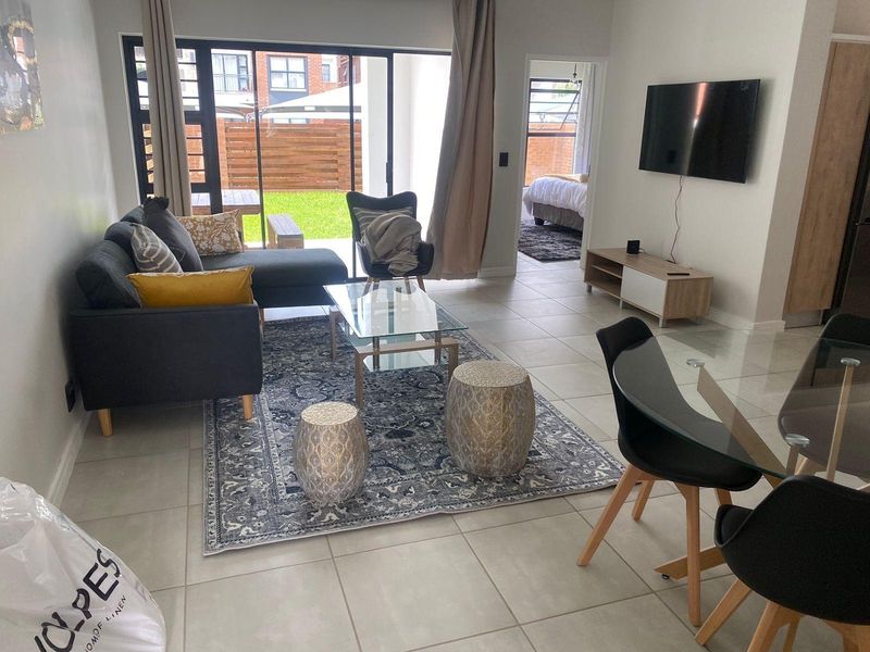 Open-plan living and dining area featuring neutral tiled flooring and large sliding glass doors providing direct access to the rear garden.