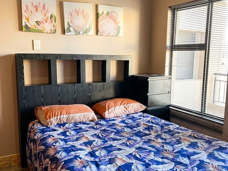 A well-maintained bedroom featuring tiled flooring, neutral wall tones, and venetian blinds, providing a comfortable and functional living space.