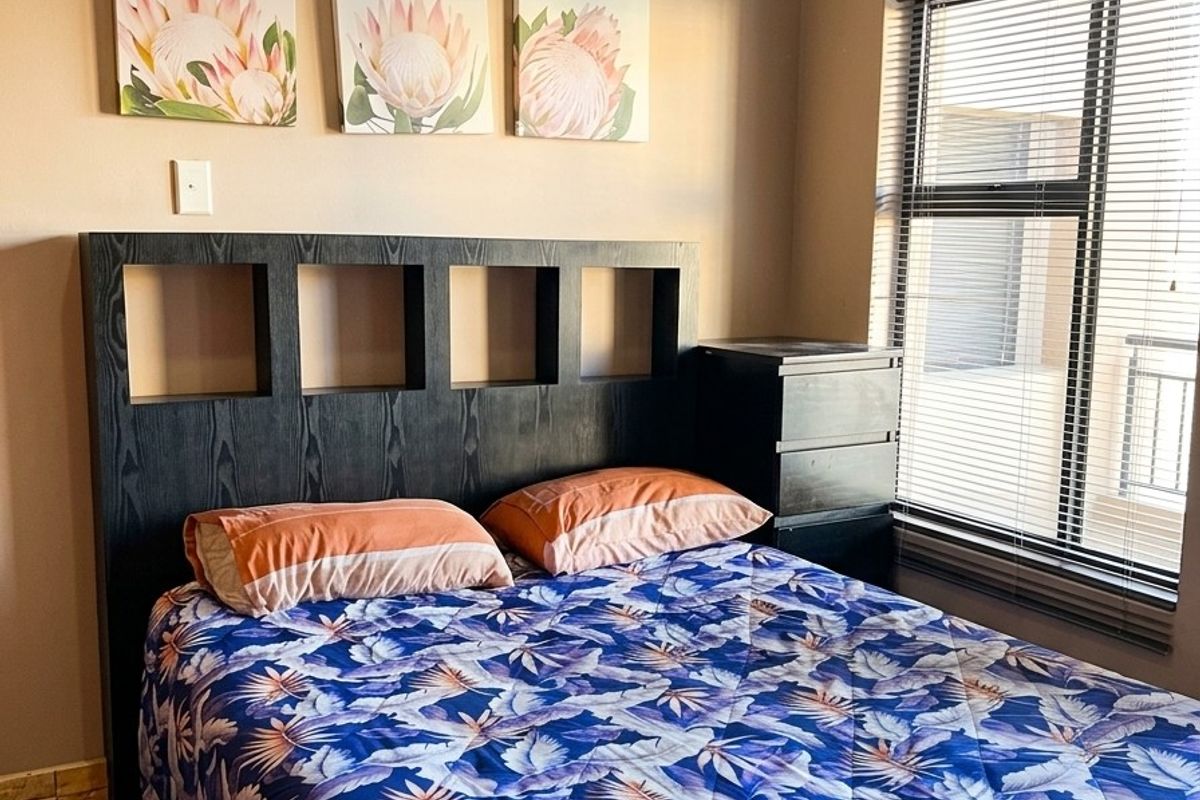 A well-maintained bedroom featuring tiled flooring, neutral wall tones, and venetian blinds, providing a comfortable and functional living space.