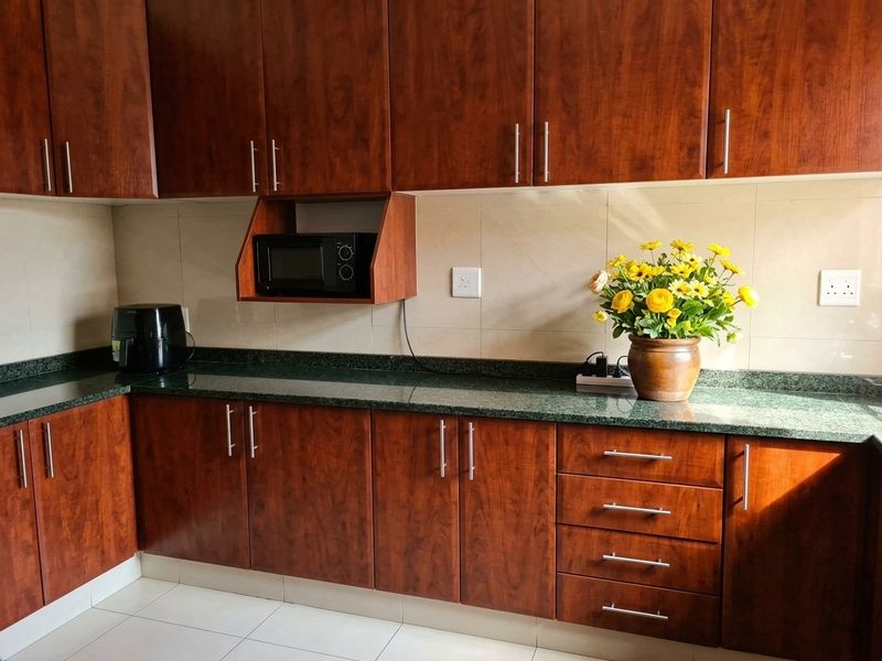 A well-maintained kitchen featuring dark wood-finish cabinetry, granite countertops, and a tiled backsplash with integrated microwave storage.