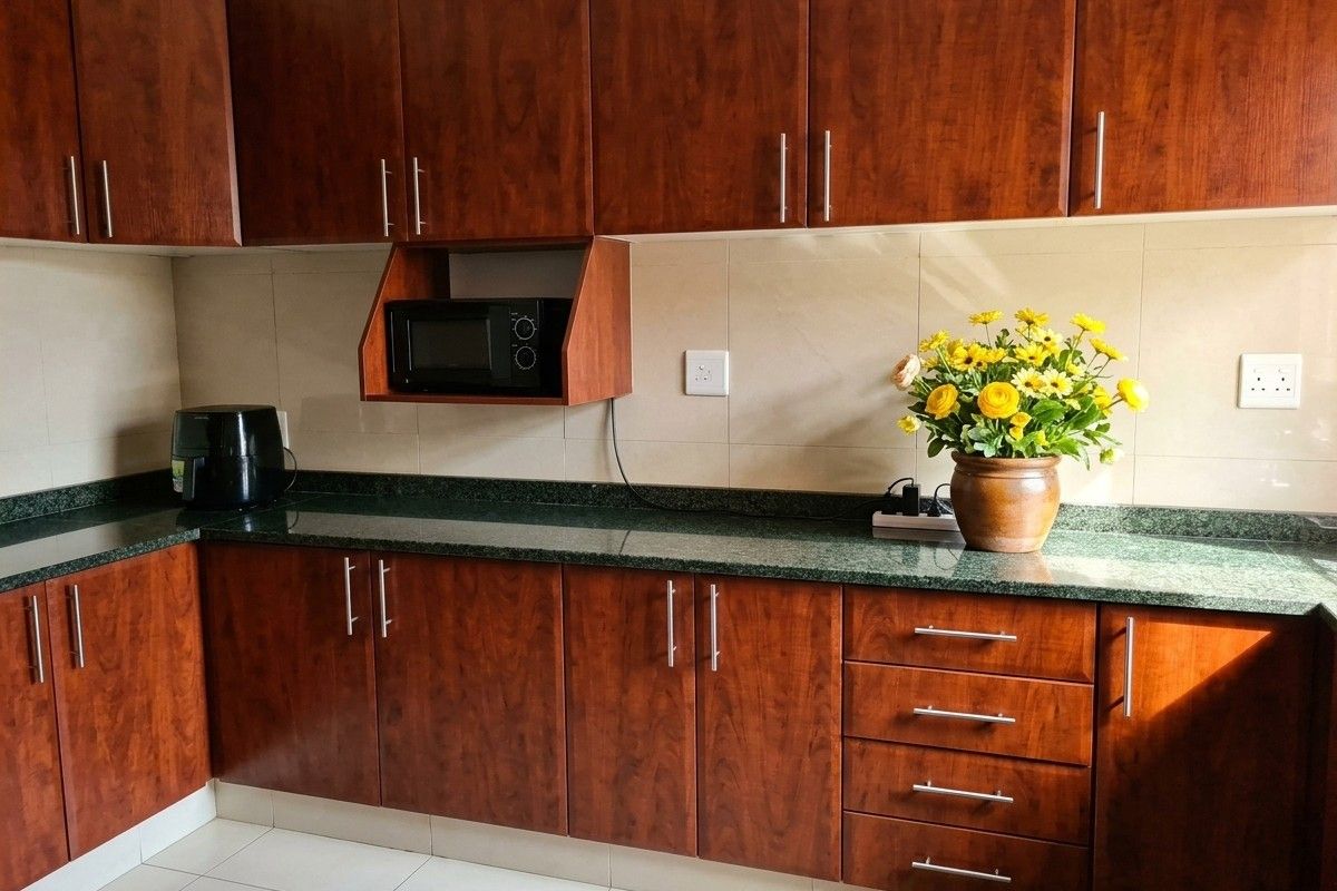 A well-maintained kitchen featuring dark wood-finish cabinetry, granite countertops, and a tiled backsplash with integrated microwave storage.