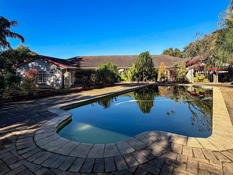 Rear exterior view featuring a swimming pool with paved surround and a single-story residential building with a tiled roof.
